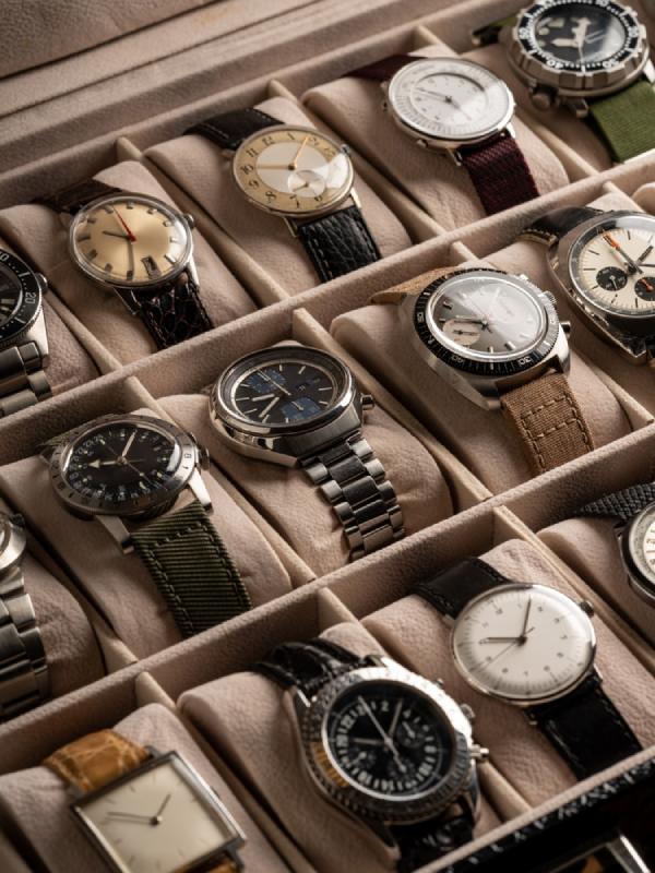 Various luxury watches are displayed in soft, beige displays, with vintage Rolex GMTs not shown.