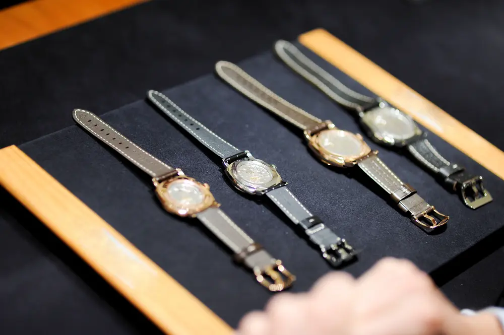 A collection of watches, the collector off-screen considering their Rolex resale value.