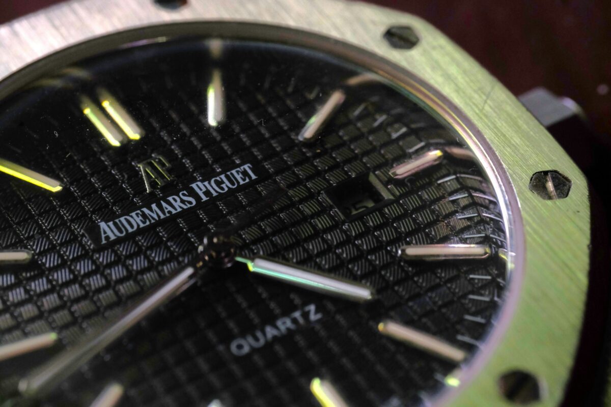 Close-up of an Audemars Piguet quartz watch with a dark patterned dial and exposed bezel screws