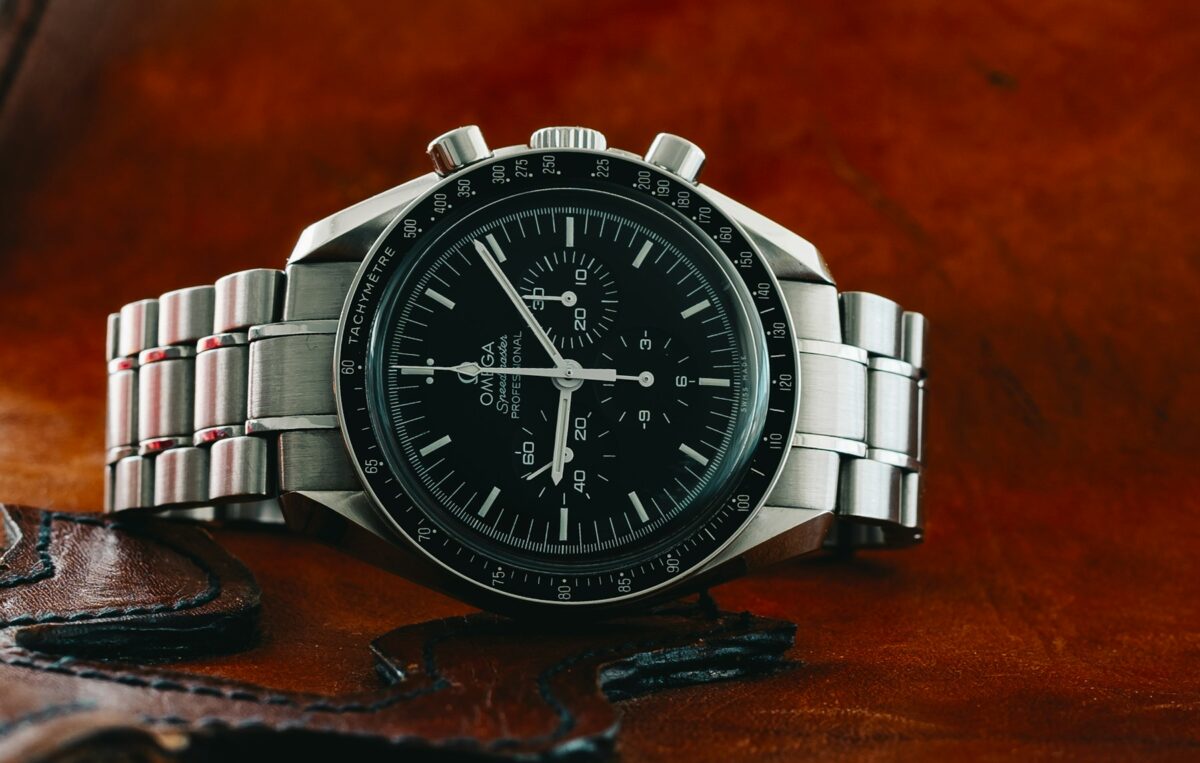 Omega Speedmaster with a black dial and stainless steel bracelet resting on brown leather